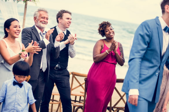 wedding guests smile and clap while looking at the married couple