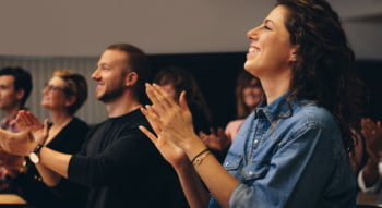 a woman smiles and claps during a corporate seminar